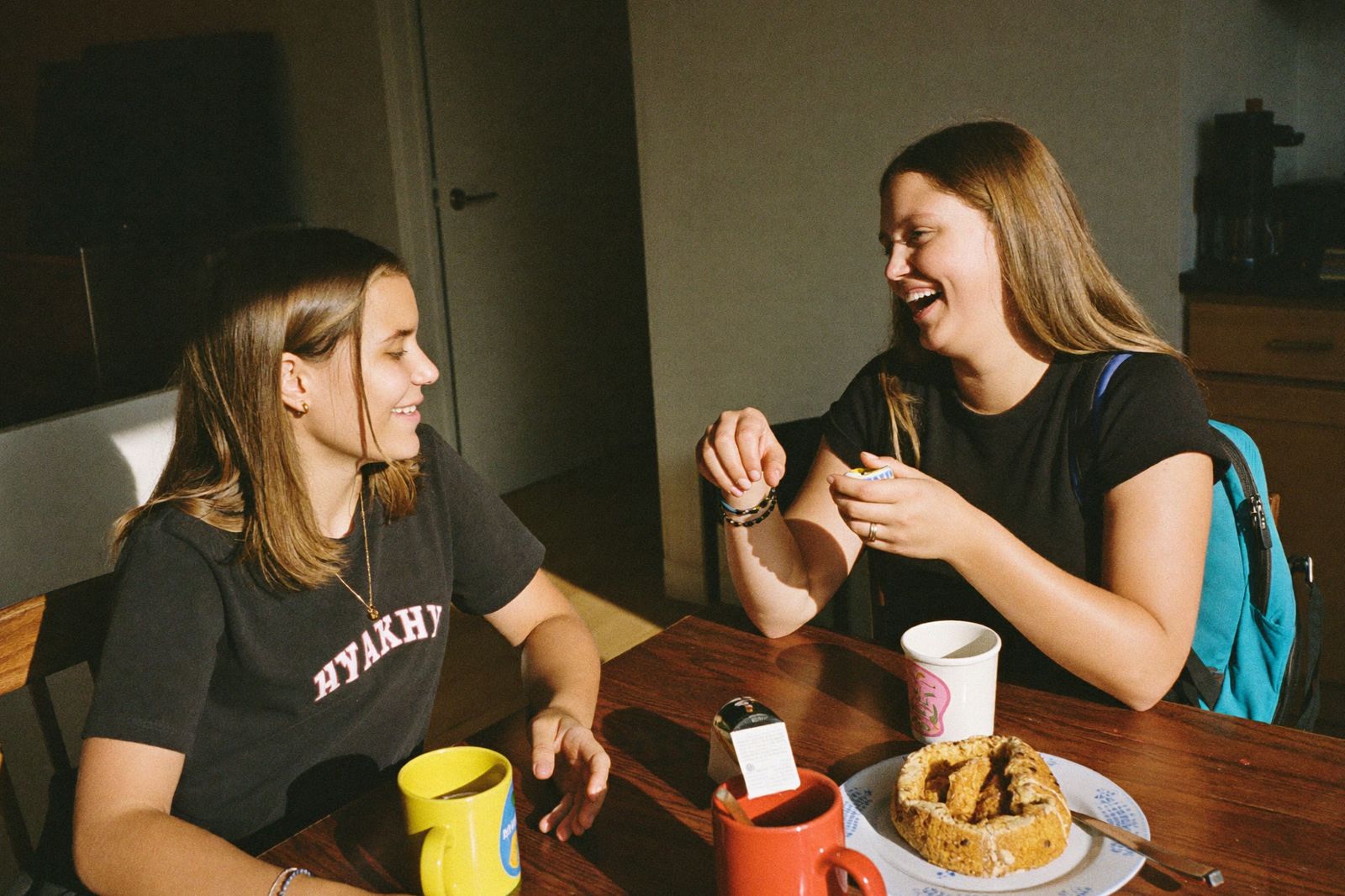 Two teens laughing together at the kitchen table after school