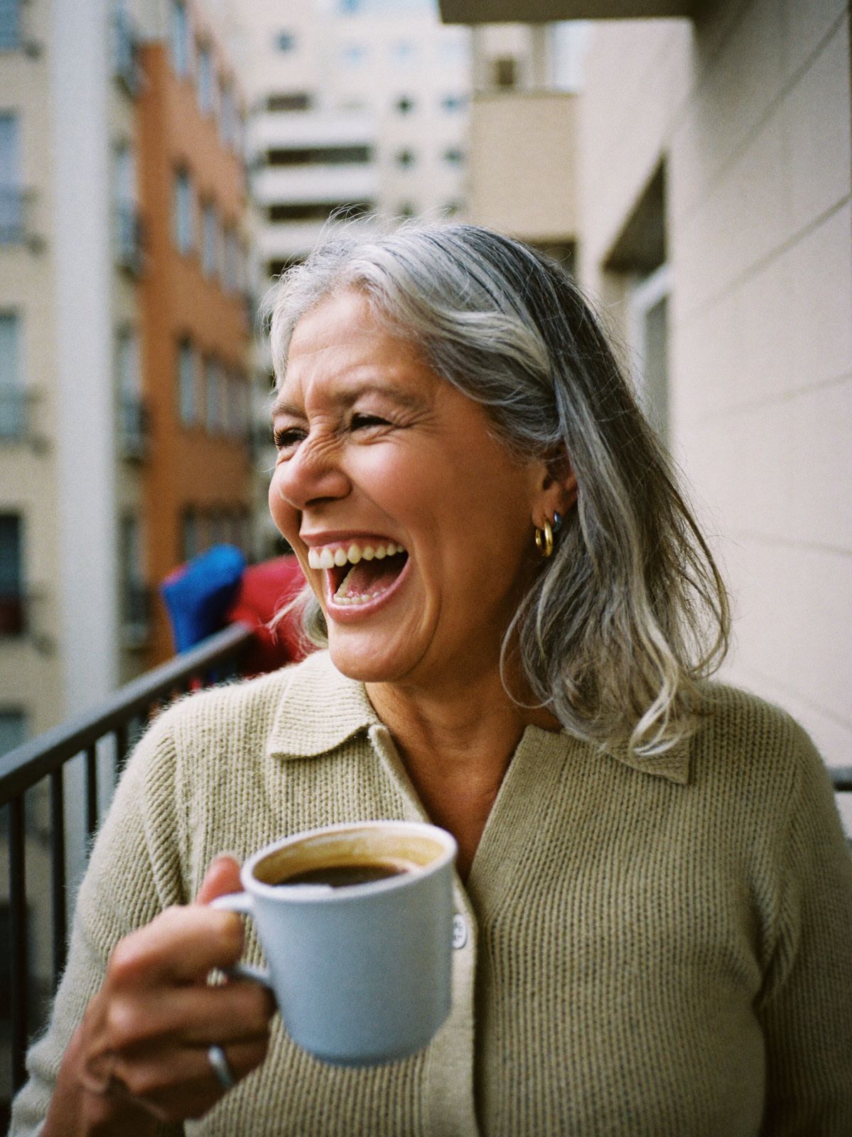 A woman in her fifties laughing over morning coffee