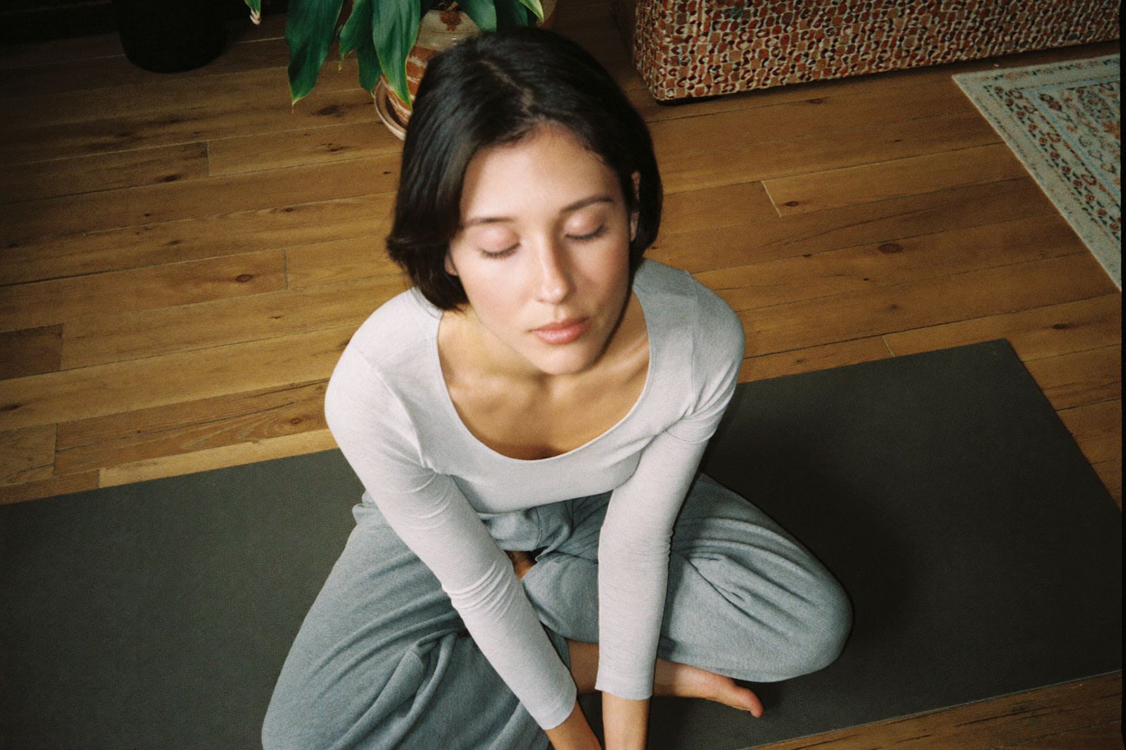 A woman breathing calmly on a yoga mat at home