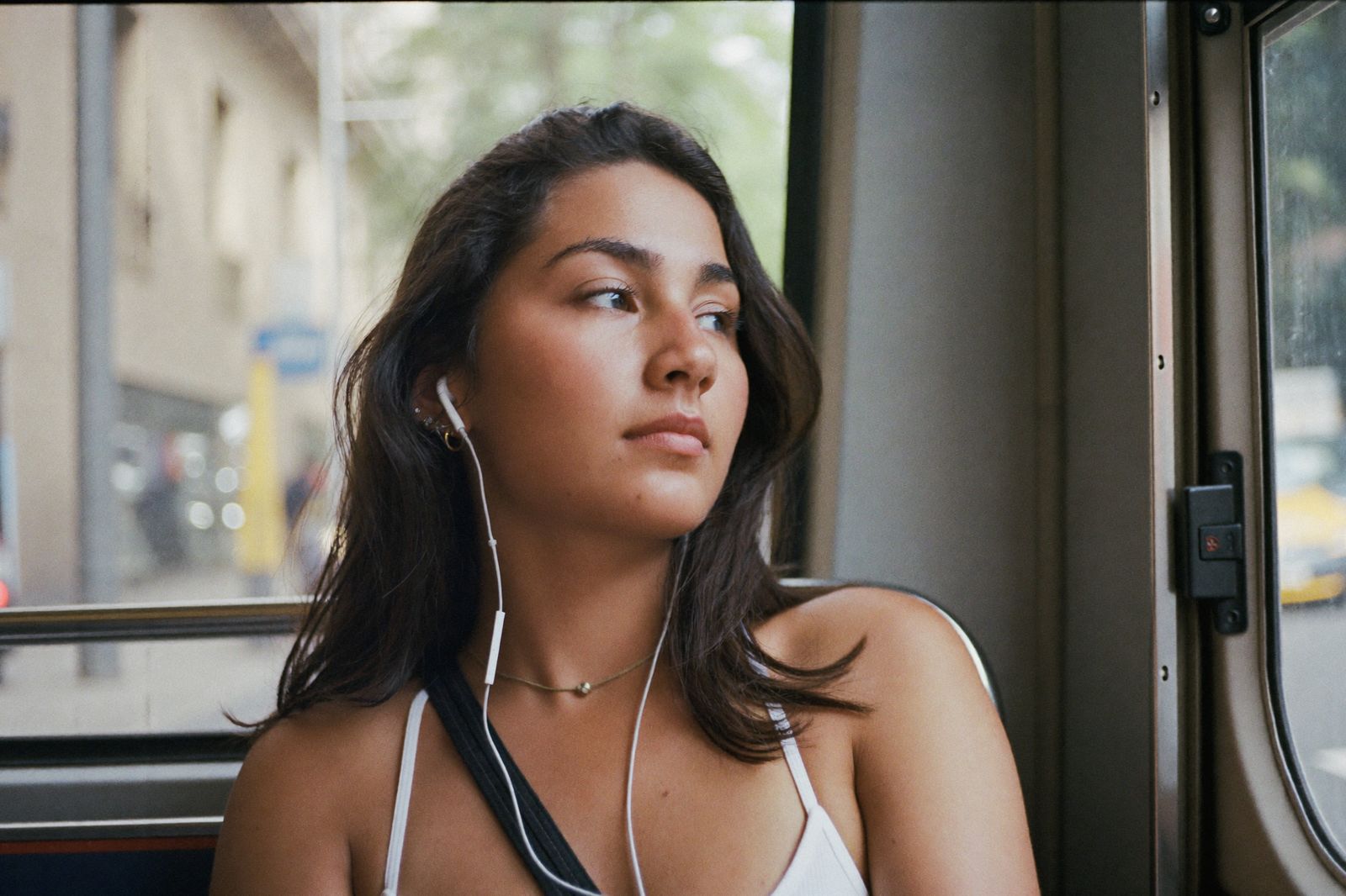A young woman looking out the window on a city bus