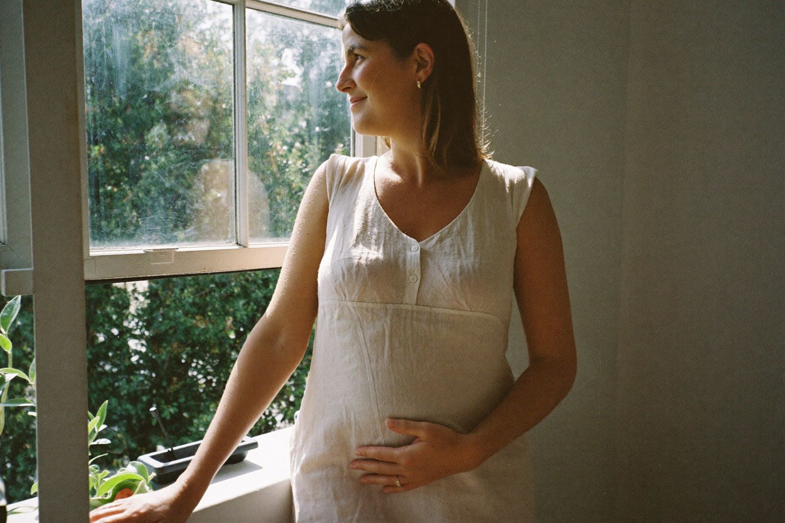 An expecting mother by a sunlit window at home